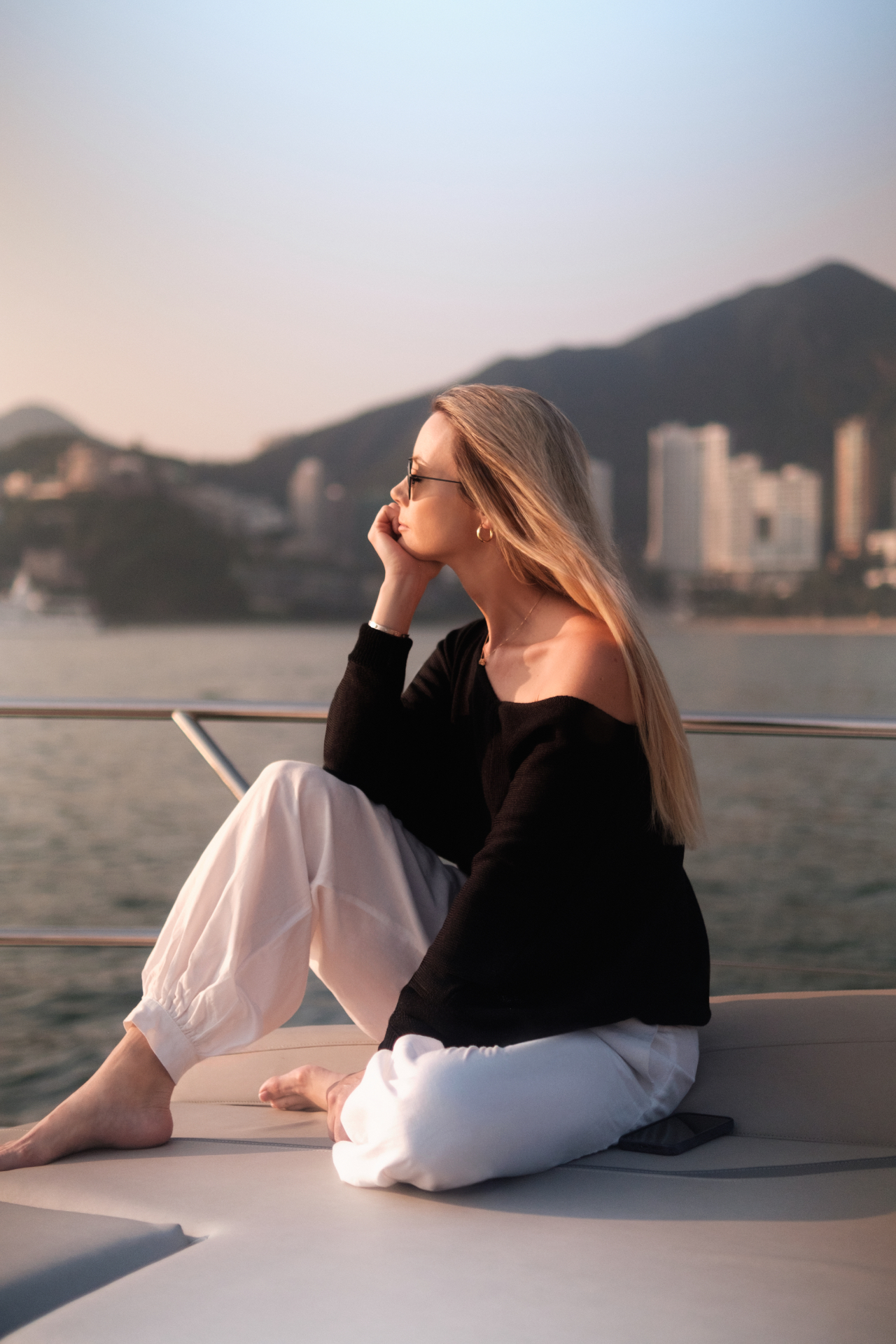 Josefine sitting on the deck of a boat, looking out over the water towards the Hong Kong shoreline